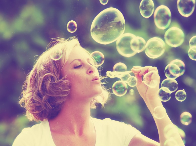 a pretty girl blowing bubbles - vintage toned with a retro insta